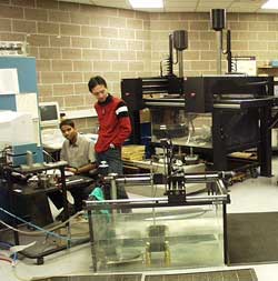 Two ultrasound researchers at the Center of Nondestructive Evaluation use ultrasonic automated scanning to inspect a part.